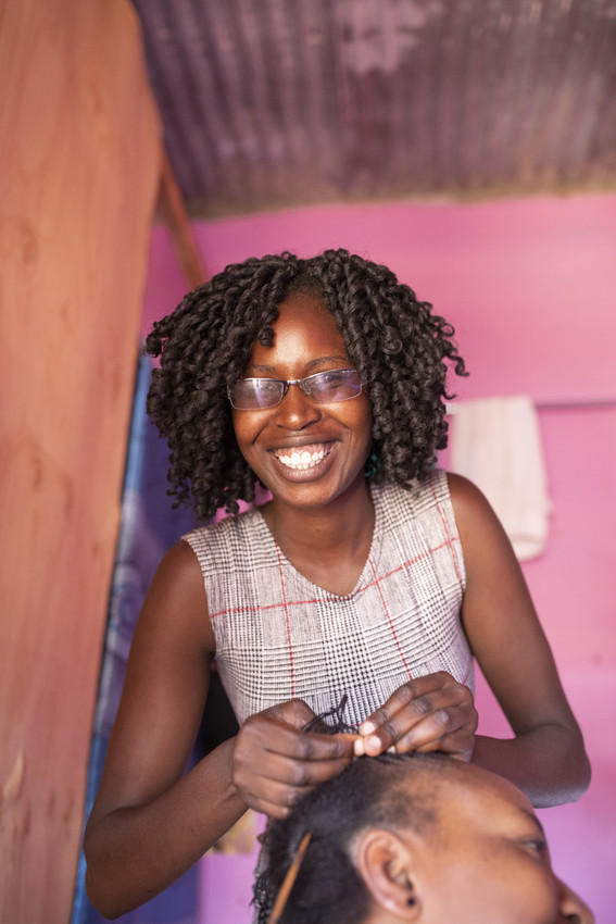 Beth, 21, shown here braiding a customer’s hair, received a ChildFund scholarship to study hairdressing, as well as startup capital to open a salon.